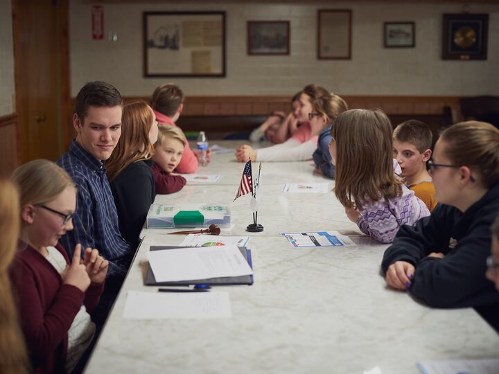 Youth holding a club meeting at a table